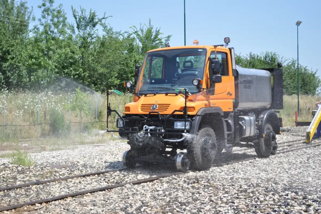 Hi rail truck operating on railway tracks with water spraying equipment for rail maintenance