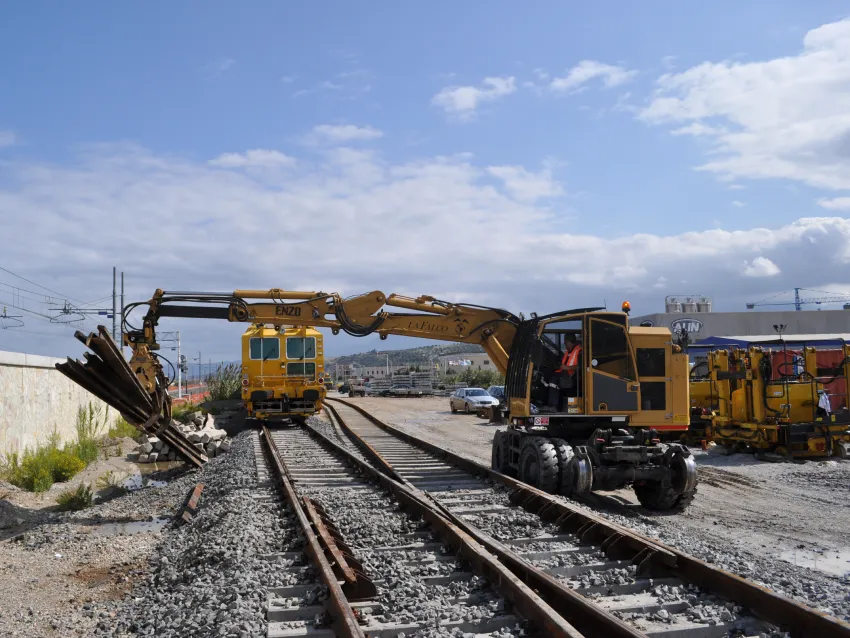 Hi rail excavator loading rail sections on railway tracks for maintenance work