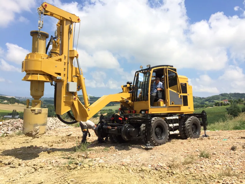 Hi rail excavator with drilling attachment for railway construction and trackside maintenance.
