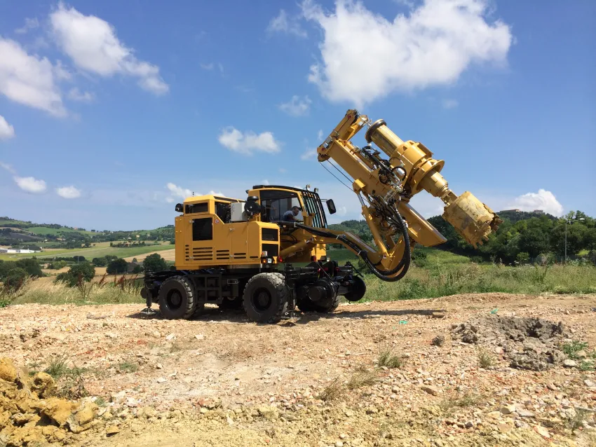 Hi rail excavator with drilling attachment for railway construction and maintenance