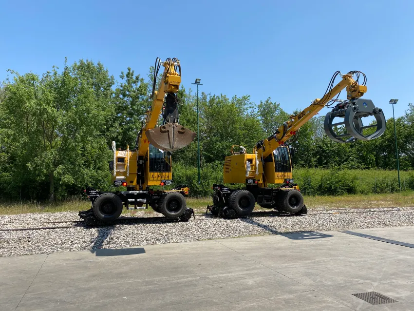 Hi rail excavators with bucket and grapple attachments for railway maintenance and material handling.