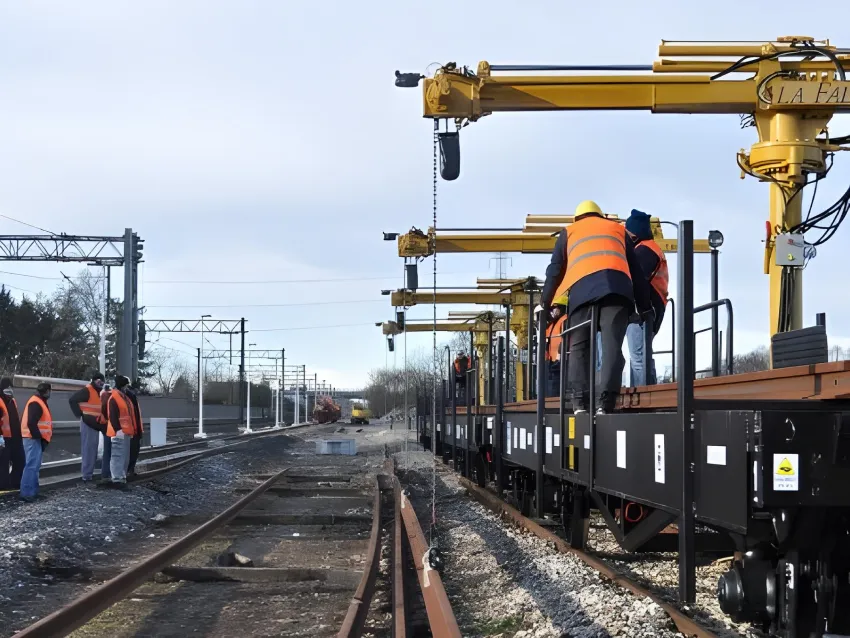 Rails loader crane positioning long rail sections during railway track installation and maintenance work